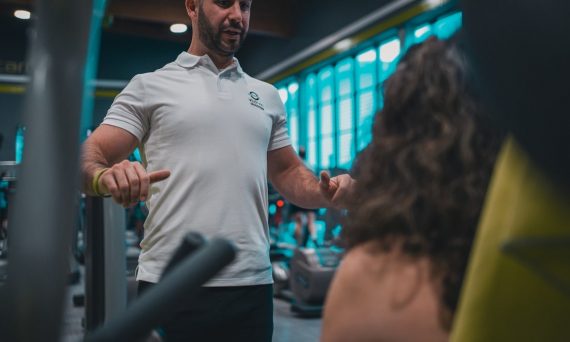 Sesión de entrenamiento en el gimnasio con un entrenador personal, enfocada en el rendimiento y el bienestar físico.